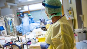 Eine Intensivkrankenschwester steht auf einer Intensivstation des RKH Klinikums Ludwigsburg im Zimmer eines Covid-19-Patienten.⇥