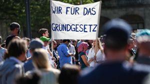 „Wir für das Grundgesetz“ steht auf einem Transparent geschrieben, das Teilnehmer der dritten Demonstration der „Querdenken“-Initiative auf dem Stuttgarter Schlossplatz in die Höhe halten. ⇥ Foto: Christoph Schmidt